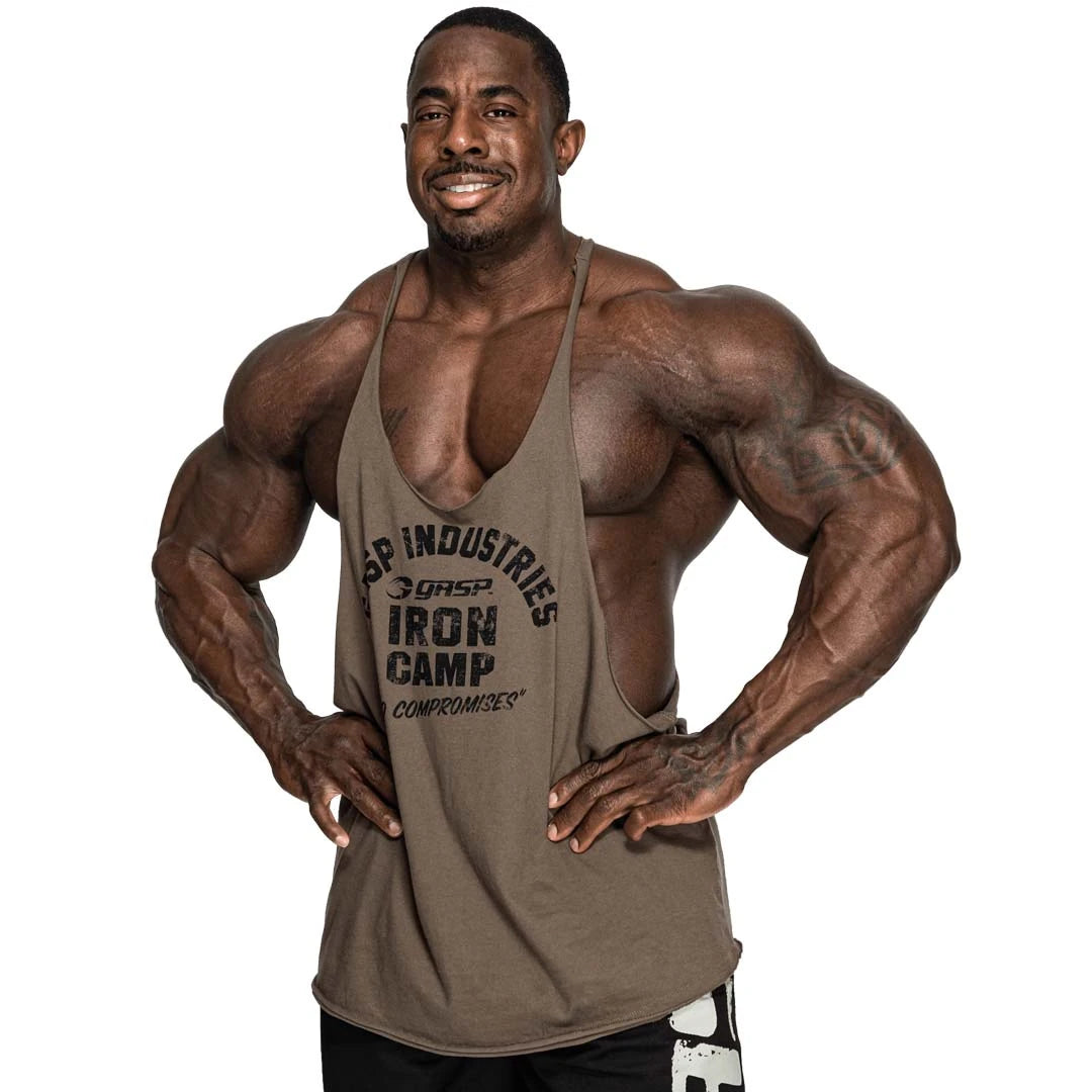 GASP Stringer Tank Washed Green, vihreä puuvillainen stringer-hihaton mustalla painatuksella lihaksikkaan miehen yllä.