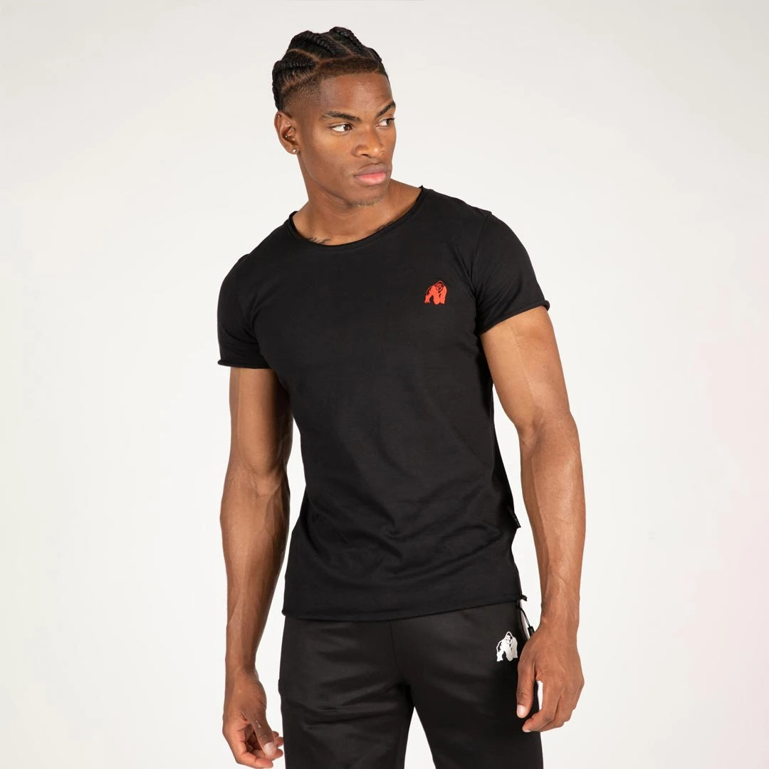 Mies yllään Gorilla Wear York T-Shirt Black, pehmeää puuvillaa, punainen logo, slim fit -istuvuus ja raakareunat.