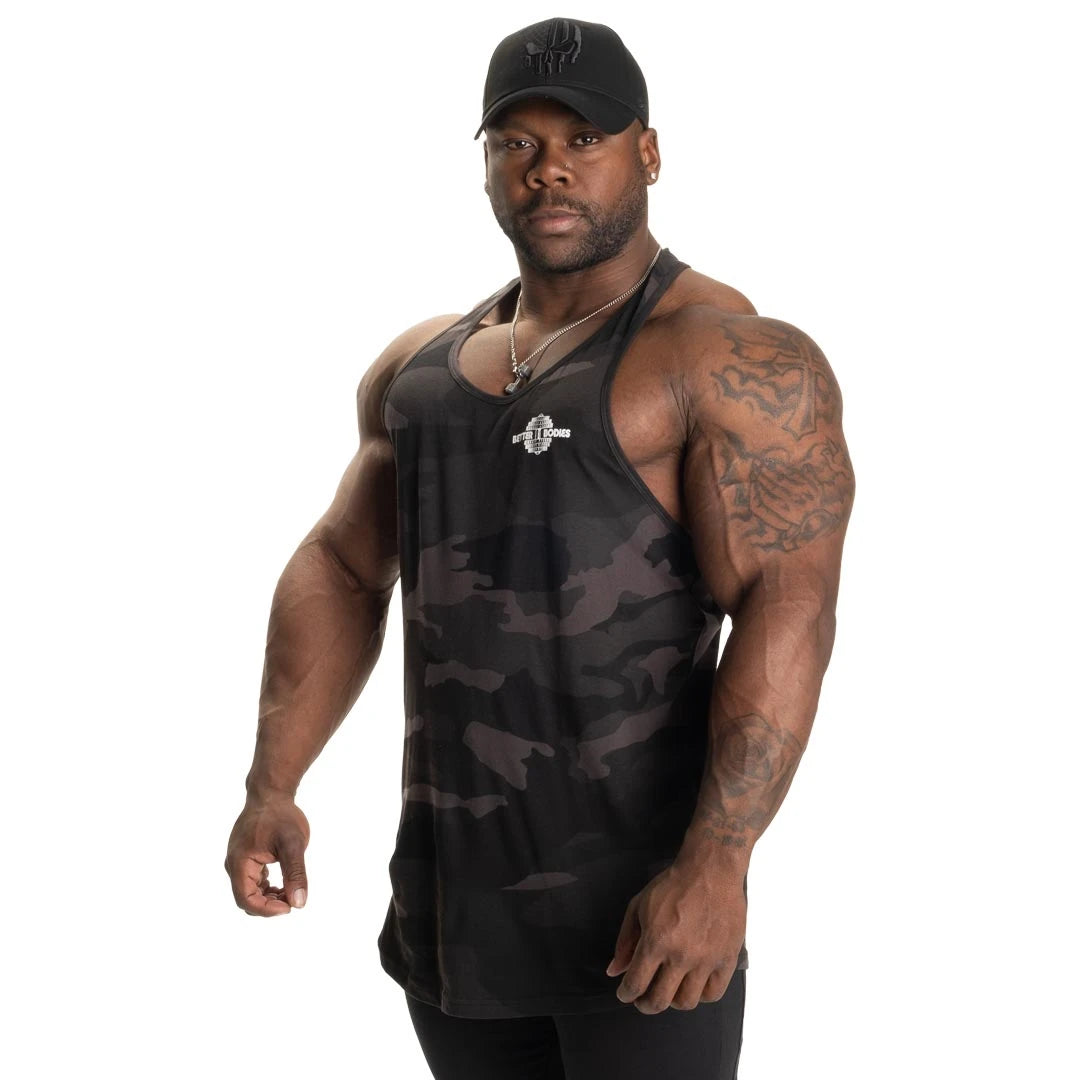 Better Bodies Essential T-back V2 Dark Camo -treenitoppi tummalla maastokuviolla ja pehmeästä puuvillasta miehen yllä., kuva 4/6