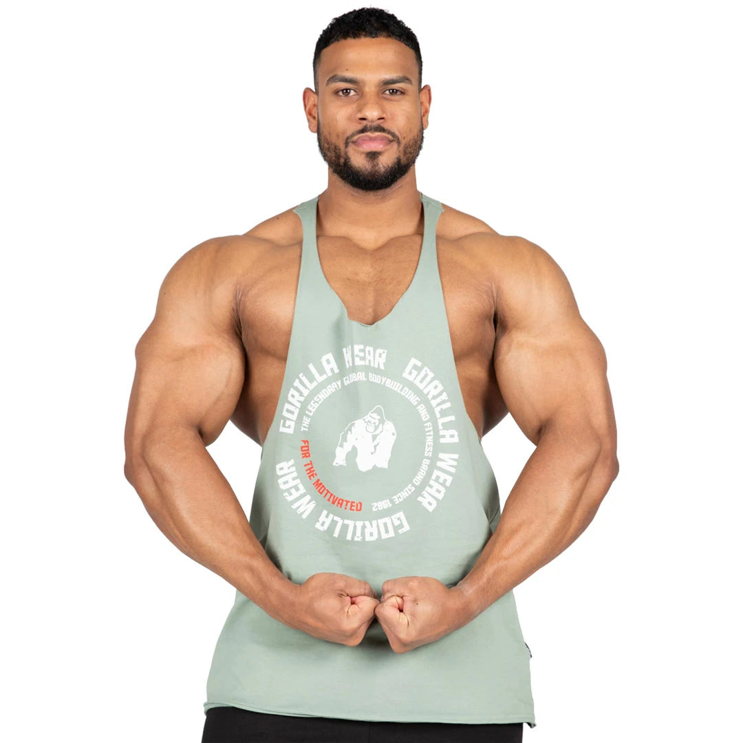 Mies käyttää vihreää Gorilla Wear Melrose Stringer Green -puuvillatoppia valkoisella painatuksella ja syvillä kädenteillä., kuva 1/7