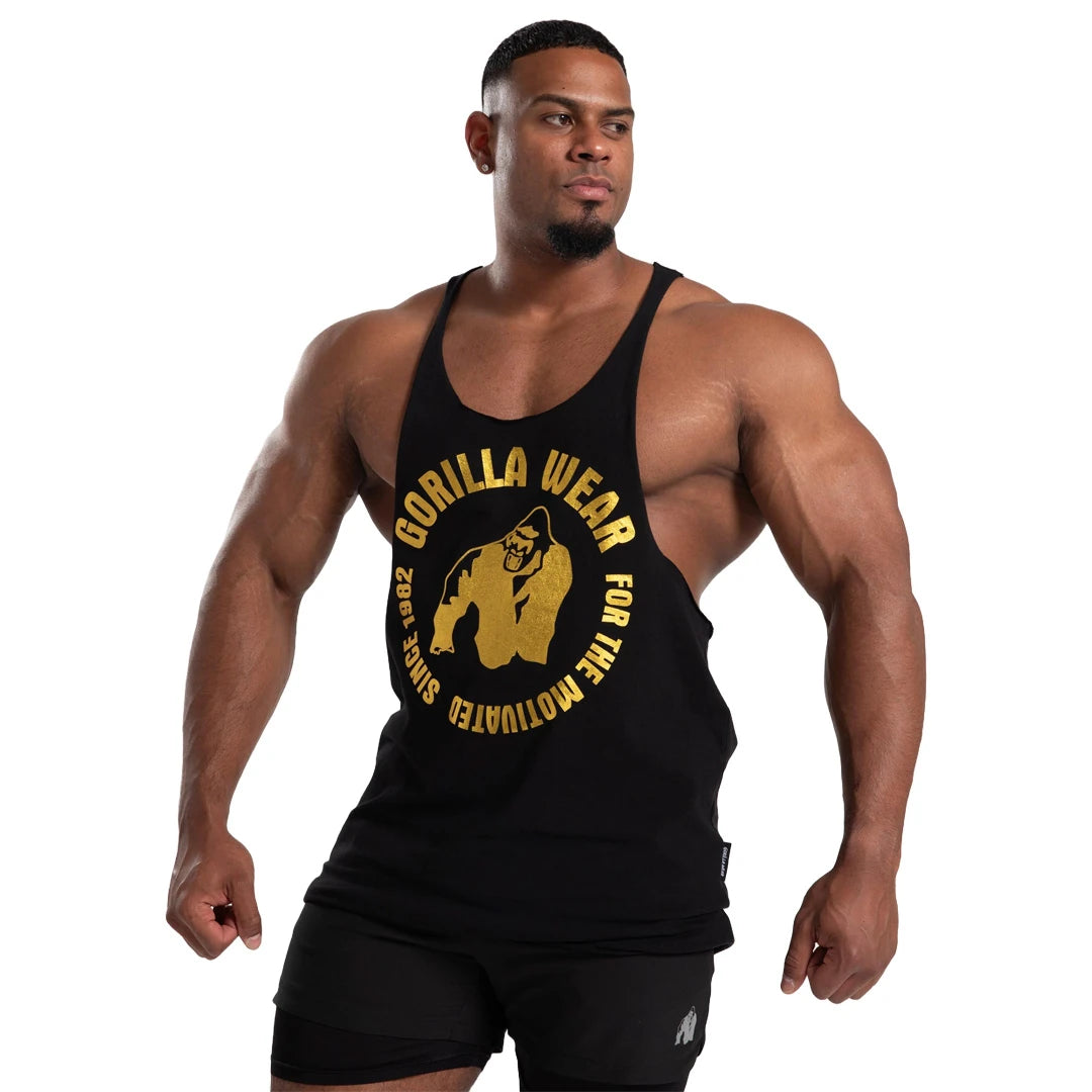 Gorilla Wear Melrose Stringer Black Gold, musta treenitoppi isolla kultapainatuksella lihaksikkaan miehen yllä., kuva 1/7