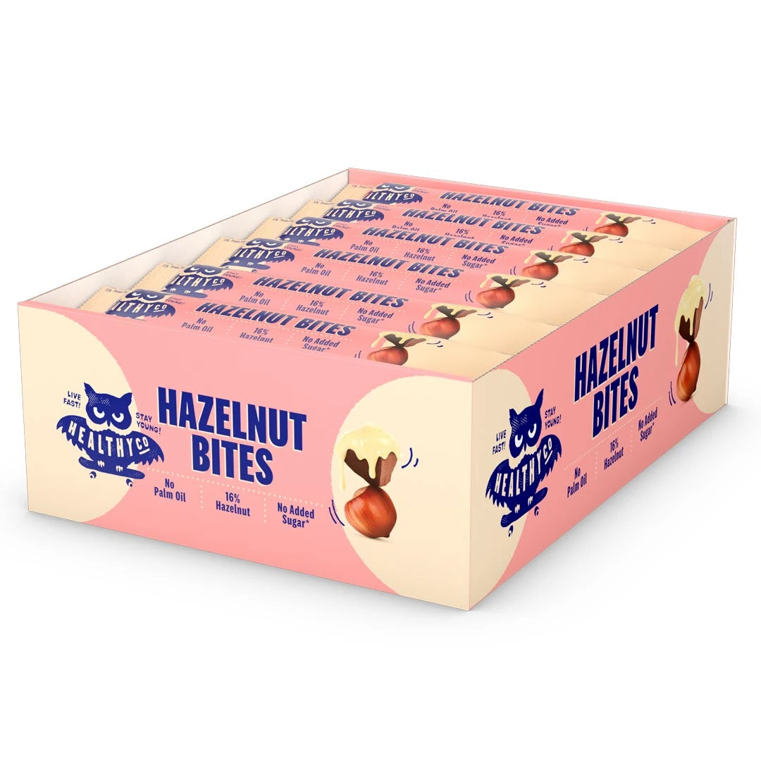 18 x HealthyCo Hazelnut Bites 21 g vaaleankeltaisessa ja vaaleanpunaisessa laatikossa täynnä suklaapaloja.